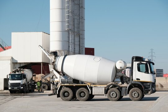 White concrete mixers standing by a modern concrete plant.	