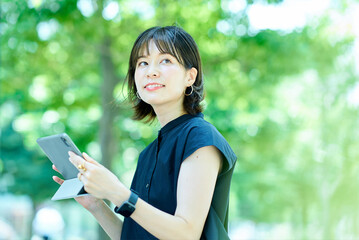 屋外でタブレットPCを操作する若い女性