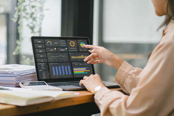 The female analyst utilizes a computer and a dashboard for business data analyze and a data management system with KPI. The concepts of technology, finance, operations, sales, and marketing.