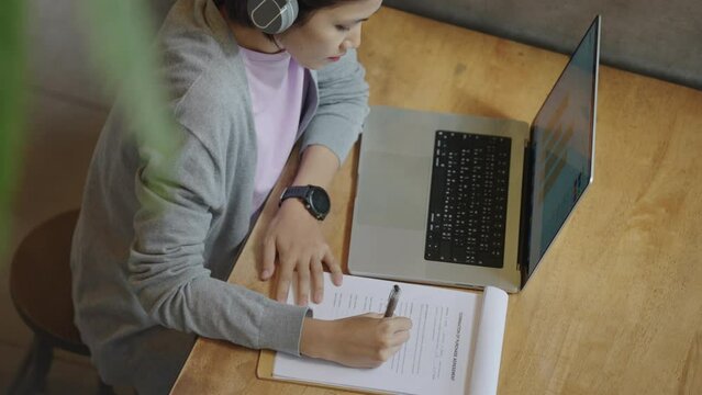 Asian Student female wear headphones learn watching online webinar webcast class looking at laptop,Asian Young Woman studying online at home