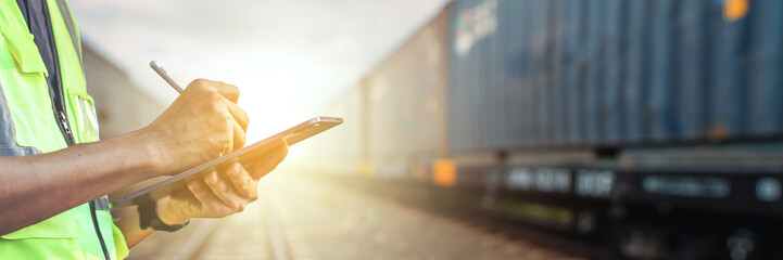 A Rail Transport An Engineer uses a Tablet to Monitor and analyze the Information System of a Networked container Freight Train. Modern Industry and transport for Business Logistics concept.