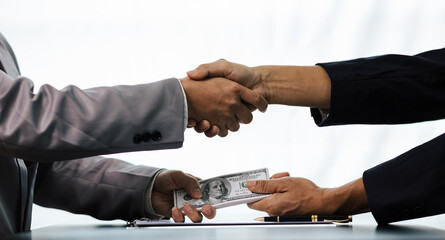 Asian businessmen shaking hands and accepting bribes at table concept of corruption