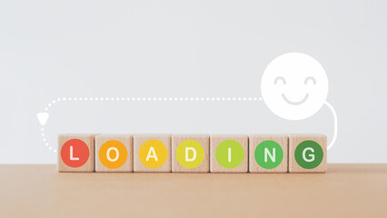 loading text in multi color circle on wooden cube block with smiling face above, for wellness,...