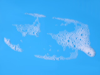 white foam from soap isolated on a blue background