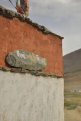 Mani stone placed on the wall. Carved stone with Tibetan script.