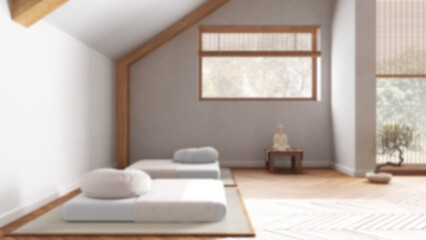 Blurred background, minimal meditation room in attic apartment. Tatami mats, pillows and table with decors. Wooden beams and window. Japandi interior design