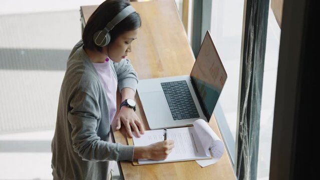 Asian Student female wear headphones learn watching online webinar webcast class looking at laptop,Asian Young Woman studying online at home