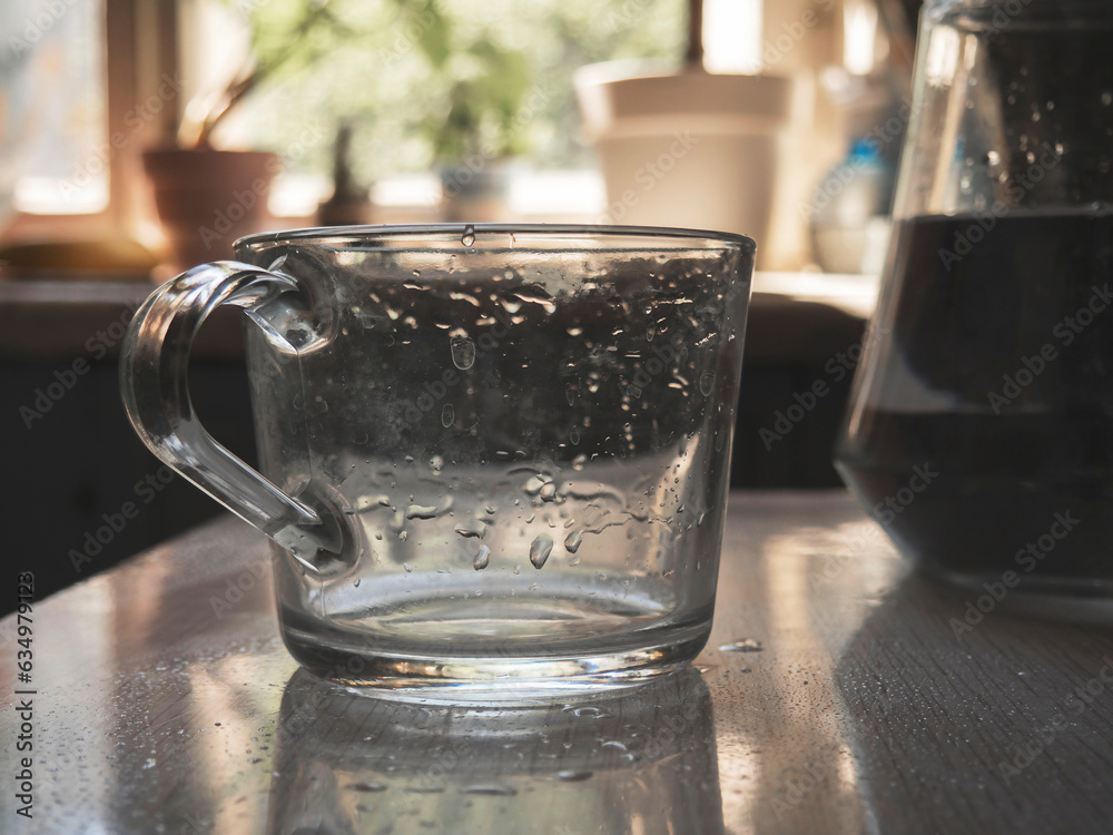 Wall mural Wet mug on the table with a pitcher of water. Art photo