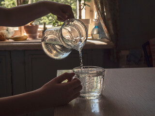 Man's hands pouring water from a pitcher into a glass. Lifestyle, art photo.