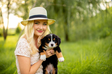 A beautiful girl with a Bernese Mountain Dog puppy is playing in nature. Love for dogs. Animal protection concept. Pet on a walk