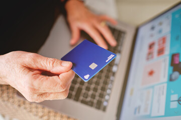 Palma, Baleares, Spain, November 20, 2020: Adult woman holding a Paypal card with her hand in front of the computer about to pay for a purchase