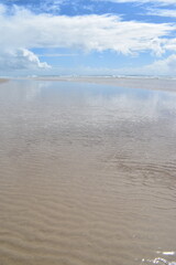 beach with an expanse of reflected clouds on wet sand