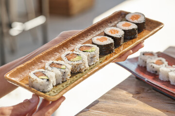 Crop person with sushi set on plate