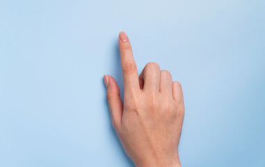 Close up of female hand pointing on isolated blue background