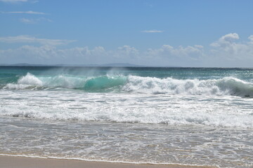 waves with spray and foam on a wide beach