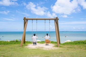 海のブランコに座る男女
