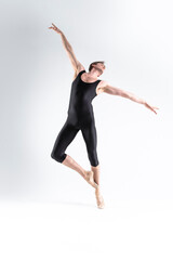 Obraz premium Ballet Dancer Young Athletic Man in Black Suit Posing in Stretching Dance Pose Studio On White.
