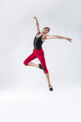Fototapeta na wymiar Ballet Ideas. Contemporary Ballet of Flexible Athletic Man Posing in Red Tights in Dance Pose With Hands Lifted on One Feet in Studio on White.