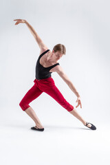 Fototapeta na wymiar Concentrated Contemporary Ballet Dancer Flexible Athletic Man Posing in Red Tights in Ballanced Dance Pose With Hands Inclined In Line on White