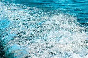 Waves on the sandy beach. Water background, blue sea water. Beautiful texture of sun glare on the water and sea foam.