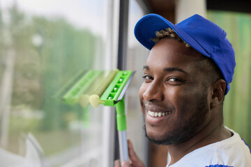 Dark-skinned handsome guy working with brush in hand wash windows is engaged in cleaning. Cleaning...