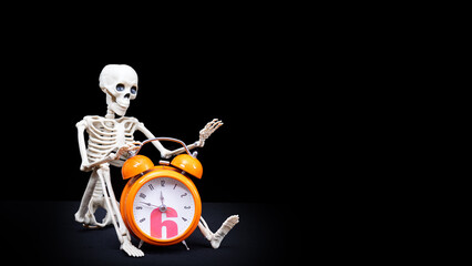 A human skeleton waving his hand, greeting holding an orange alarm clock on a black background