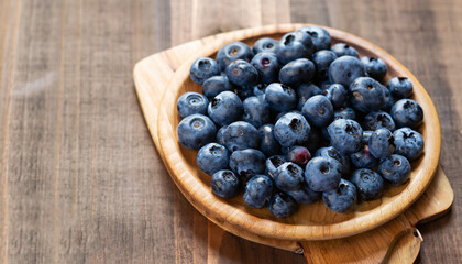 Blueberries on a board over wooden table.
