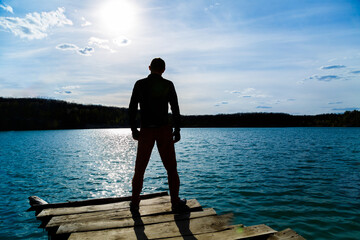 Silhouette of a man against the sky and blue water