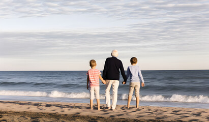 Grandfather walking with grandchildren at beach. Concept of grandfather day, grandparents day