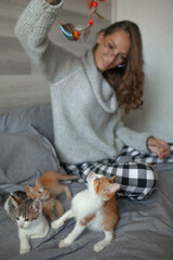 The young girl have fun with kittens in the bed