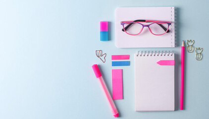 Back to school. A set of stationery on a blue background. Blank white notebook, bright pink pencils, selective focus