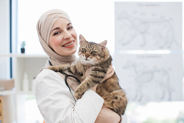 Arabian lady with cat in hands standing at pet care facility