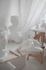 Fototapeta na wymiar Capturing the ambiance of a sculptor's studio, with gesso masks, plaster busts, and tools like a mallet and chisel, all illuminated in a soft, luminous setting