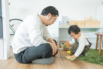 春の昼の家の部屋で一緒に座っておままごとをして遊ぶ日本人の親子