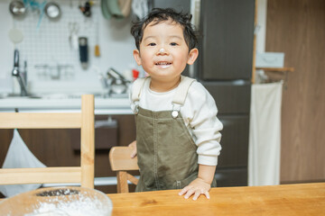 春に家の中でお菓子作り中に顔にクリームが付いて笑う黒髪のアジア人の子供