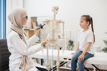 Physician showing ribs on anatomical model to preteen girl
