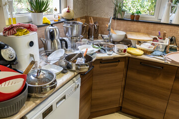 Kitchen countertops. Sink and counter of home kitchen full of messy and dirty plates, pots