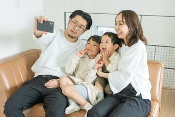 冬の午後、寄り添って座って4人で携帯で写真を撮るアジア人の家族