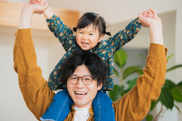 秋の自宅のリビングで肩車をして楽しそうに遊ぶ日本人の父親と娘の親子