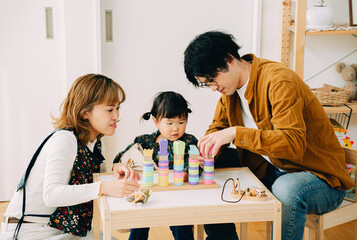 秋の午後、子ども部屋で座って3人で真剣におもちゃで遊ぶ日本人の親子