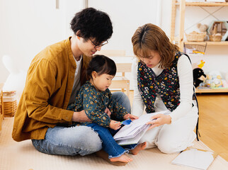 冬の日中、自宅の部屋で一緒に本を読む日本人の3人家族