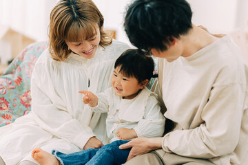 Fototapeta premium 秋の午後、リビングで一緒に座る幸せそうな白い服を着た日本人の3人家族