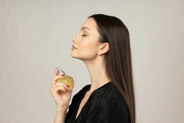 Young woman applying perfume on white background