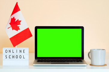 Open laptop with green screen chroma key on the table next to Canada flag and display that says...