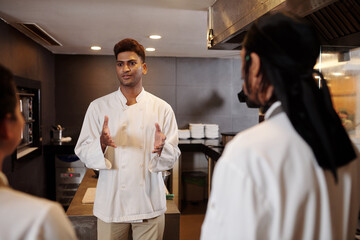 Fototapeta na wymiar Indian restaurant chef talking to his team to cheer them up before long shift