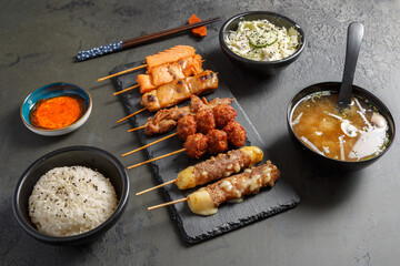 Assortiment de Yakitori japonais au saumon, au boeuf fromage, au poulet sur une ardoise. Servi avec...