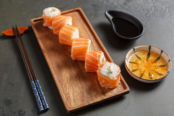 California rolls au saumon sur une ardoise avec une sauje soja et baguettes. Cusine japonaise.