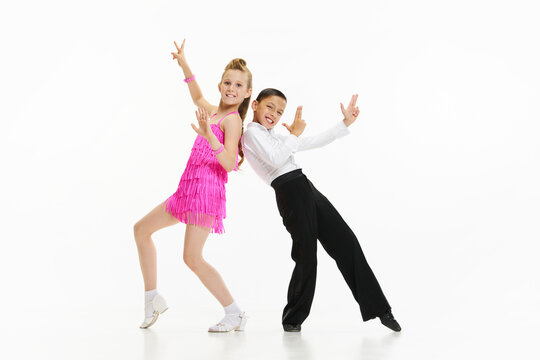 Beautiful, stylish children boy and girl dancing retro style dance, performing against white studio background. Concept of childhood, hobby, active lifestyle, performance, art, fashion