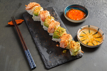 California rolls au saumon sur une ardoise avec une sauje soja et baguettes. Cusine japonaise.