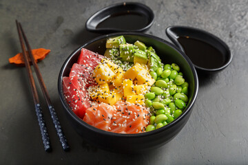Poke bowl japonais avec des sauces soja et baguettes.